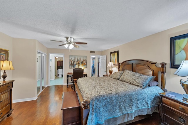 bedroom with a textured ceiling, ceiling fan, dark hardwood / wood-style floors, and ensuite bathroom