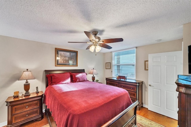 bedroom with a textured ceiling, ceiling fan, and wood-type flooring