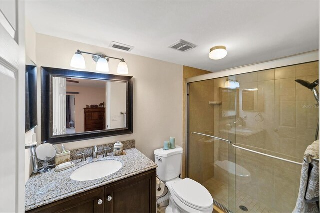 bathroom with toilet, a shower with door, and vanity