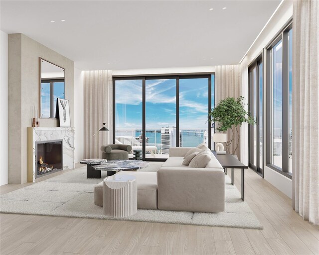 living room with expansive windows, a high end fireplace, a water view, and light hardwood / wood-style floors