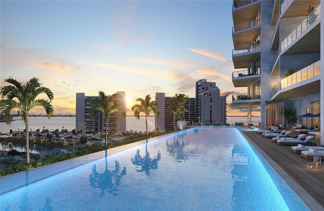 pool at dusk featuring a water view