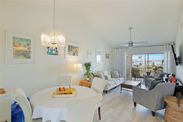 dining space with high vaulted ceiling, ceiling fan with notable chandelier, and light hardwood / wood-style flooring