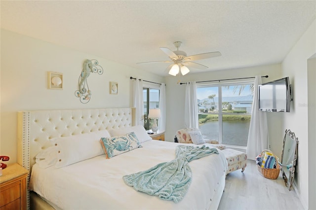 bedroom with light wood-type flooring, ceiling fan, and a textured ceiling