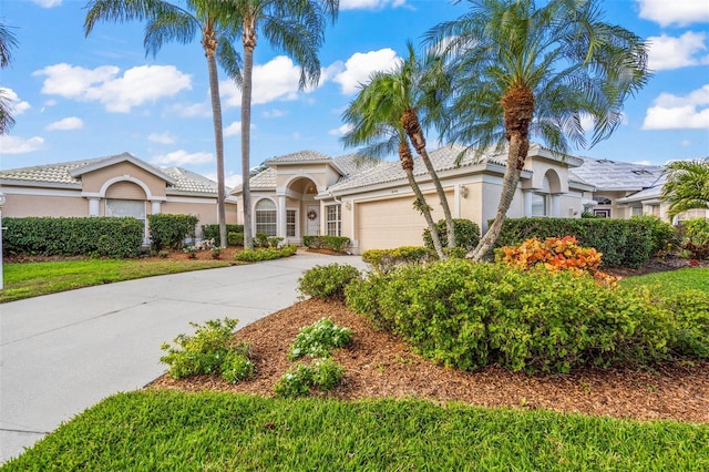 mediterranean / spanish-style home featuring concrete driveway, an attached garage, a tiled roof, and stucco siding