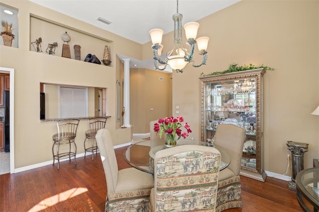 dining area featuring a notable chandelier, decorative columns, and dark hardwood / wood-style floors