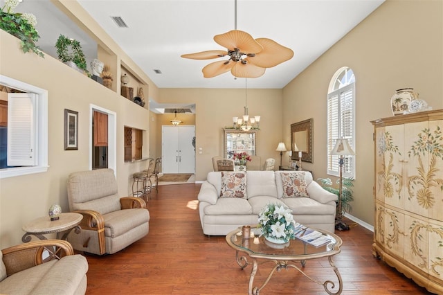 living room with ceiling fan with notable chandelier and dark hardwood / wood-style floors