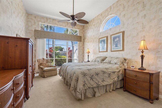 carpeted bedroom featuring ceiling fan and a towering ceiling