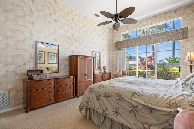 bedroom with ceiling fan, light colored carpet, and a high ceiling