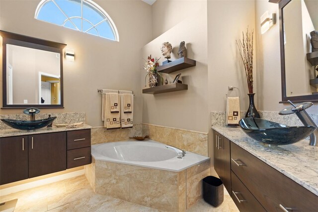 bathroom with double sink vanity, tiled bath, tile patterned floors, and a towering ceiling