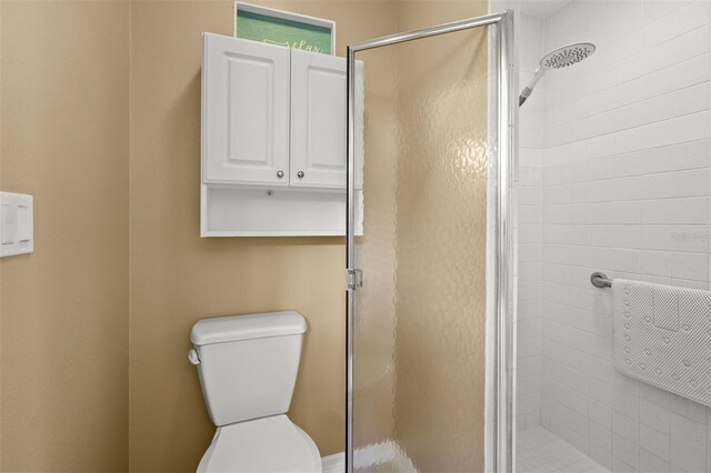 bathroom with a shower with door and toilet