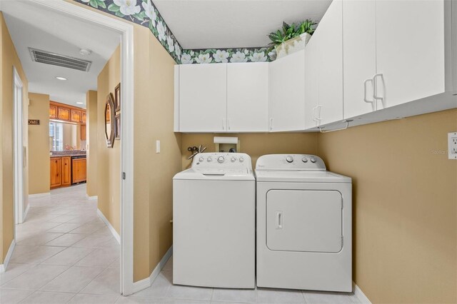 laundry room featuring cabinets, light tile patterned flooring, and independent washer and dryer