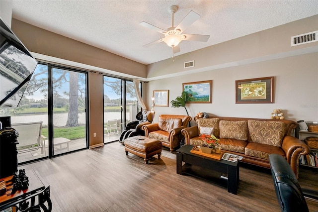 living room with hardwood / wood-style flooring, ceiling fan, a textured ceiling, and a water view