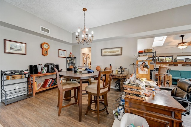 dining room with hardwood / wood-style floors, a textured ceiling, ceiling fan with notable chandelier, and a skylight