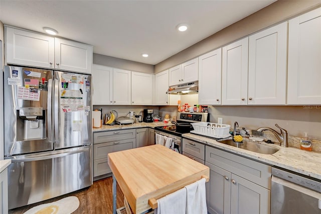 kitchen with sink, gray cabinetry, dark hardwood / wood-style flooring, stainless steel appliances, and light stone countertops