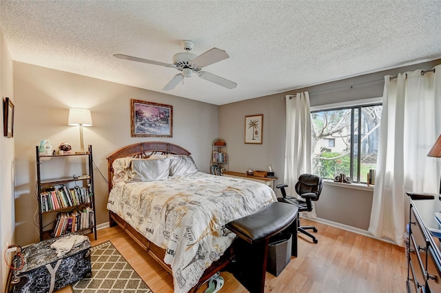 bedroom with a textured ceiling, ceiling fan, and light wood-type flooring