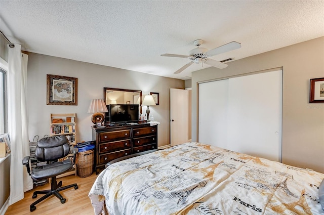 bedroom featuring a closet, a textured ceiling, light hardwood / wood-style floors, and ceiling fan