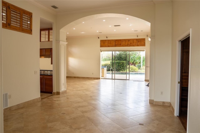 empty room with ornamental molding and a high ceiling