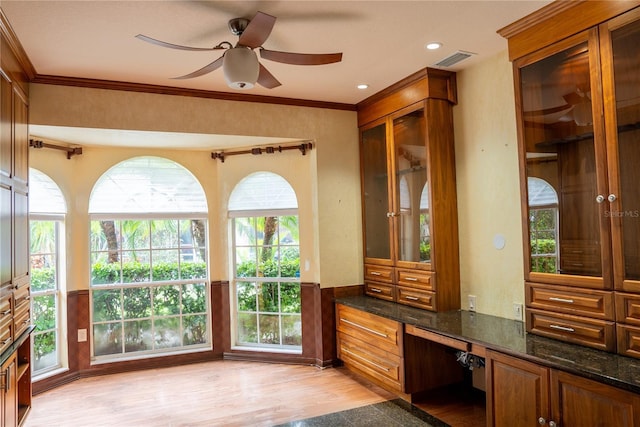 interior space featuring ornamental molding, built in desk, ceiling fan, and light wood-type flooring