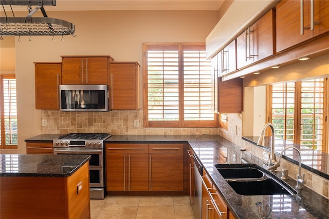 kitchen featuring stainless steel appliances, sink, decorative backsplash, and dark stone counters