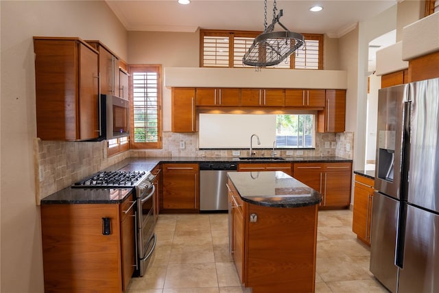 kitchen featuring sink, decorative light fixtures, ornamental molding, a kitchen island, and stainless steel appliances