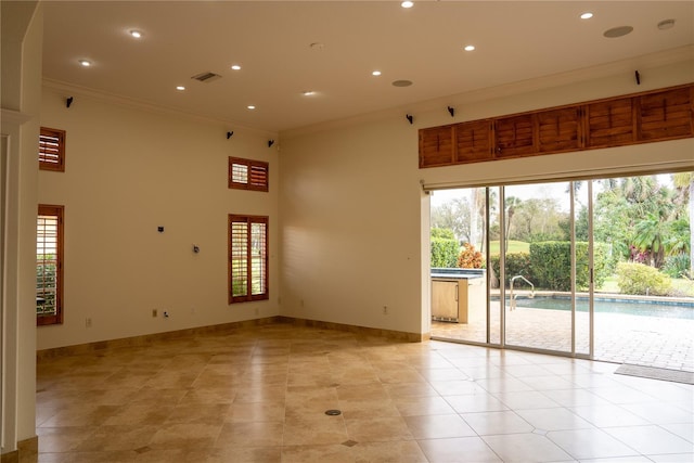 unfurnished room with light tile patterned floors, crown molding, and a high ceiling