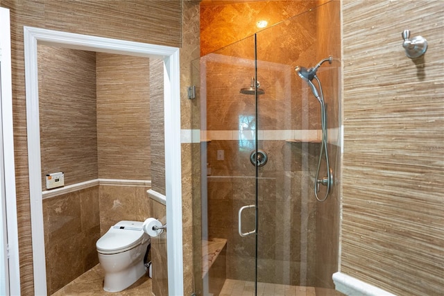 bathroom featuring a shower with shower door, tile walls, and toilet