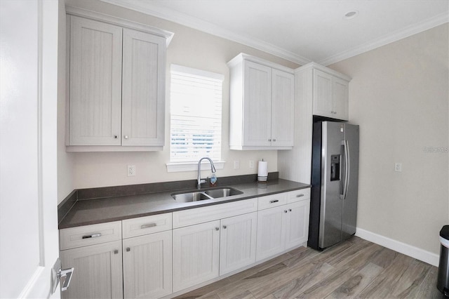 kitchen featuring white cabinets, crown molding, sink, stainless steel refrigerator with ice dispenser, and light wood-type flooring