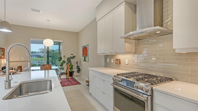 kitchen featuring sink, wall chimney range hood, high end stainless steel range oven, backsplash, and decorative light fixtures