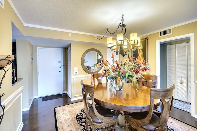 dining space featuring dark hardwood / wood-style flooring, ornamental molding, and a chandelier