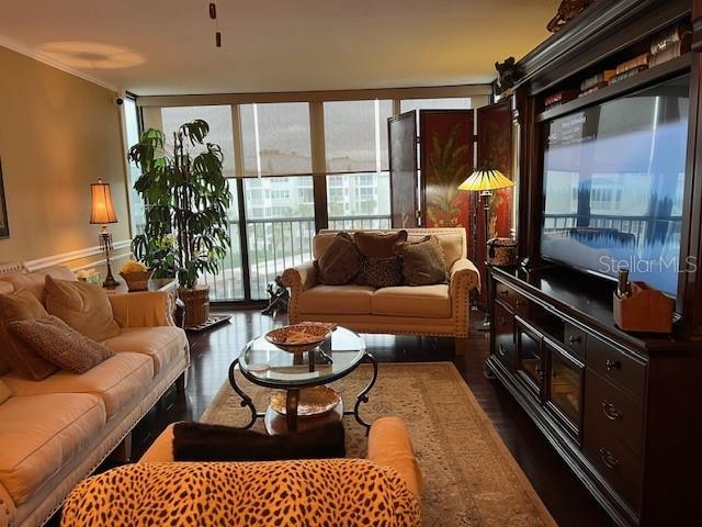 living room with dark wood-type flooring, plenty of natural light, and crown molding