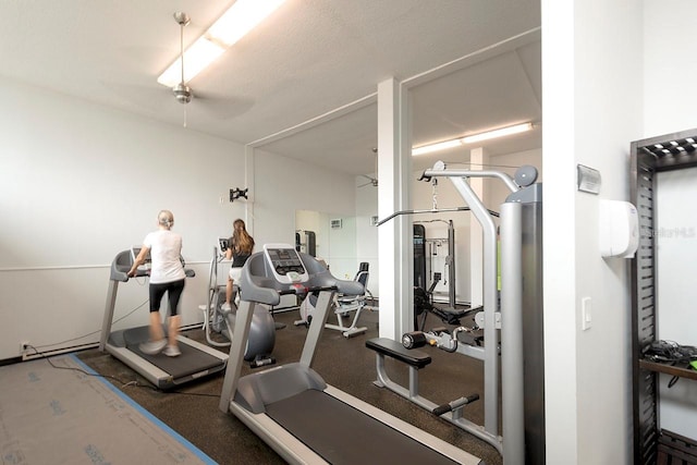 exercise room with ceiling fan and a textured ceiling