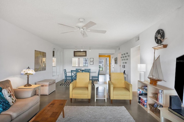 living room featuring ceiling fan, rail lighting, and a textured ceiling