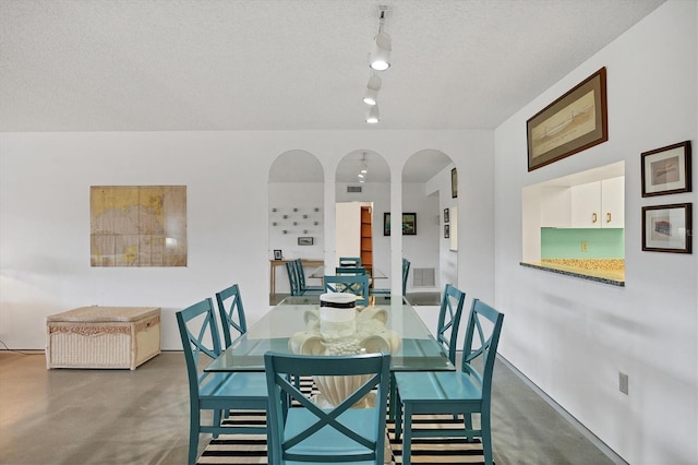 dining room with a textured ceiling and rail lighting