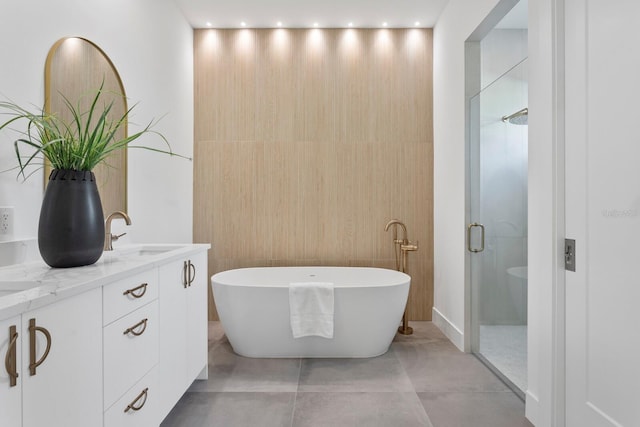 full bathroom featuring a freestanding tub, tile patterned flooring, a sink, double vanity, and a stall shower