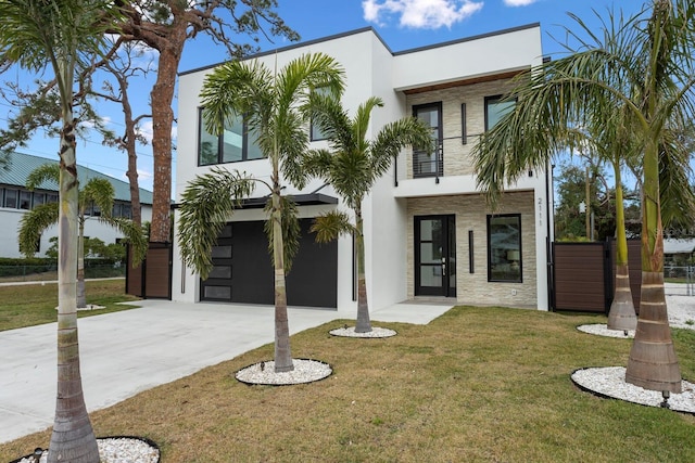 contemporary home featuring a balcony, a front lawn, concrete driveway, and stucco siding