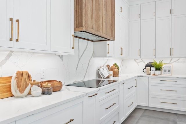 kitchen with light stone countertops, black electric cooktop, white cabinets, and decorative backsplash