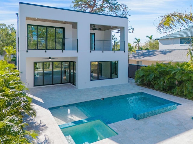 back of property with an outdoor pool, a ceiling fan, a balcony, a patio area, and stucco siding