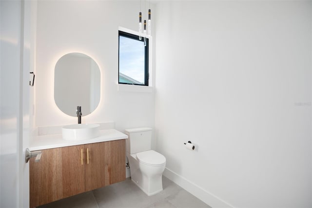 half bathroom featuring baseboards, vanity, toilet, and tile patterned floors