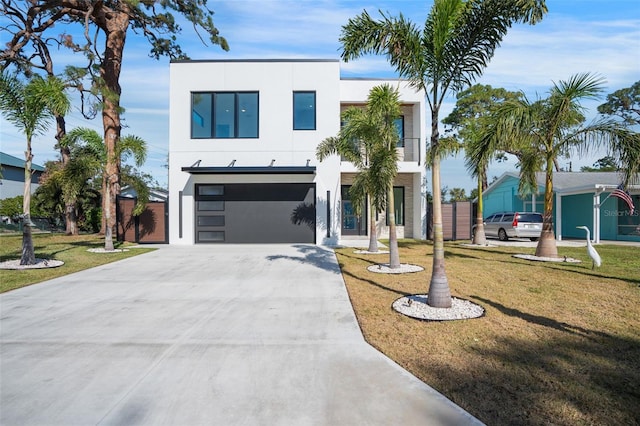 view of front of house featuring an attached garage, a front yard, concrete driveway, and stucco siding