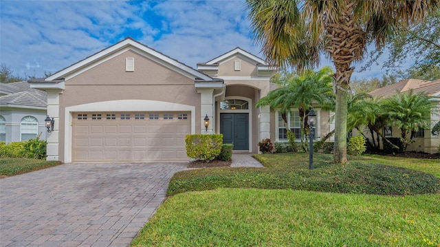 view of front of house with stucco siding, an attached garage, decorative driveway, and a front yard