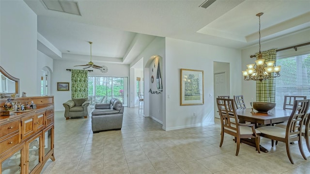 tiled dining room with a tray ceiling and ceiling fan with notable chandelier