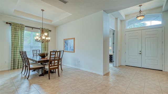 tiled dining area featuring a chandelier and a raised ceiling