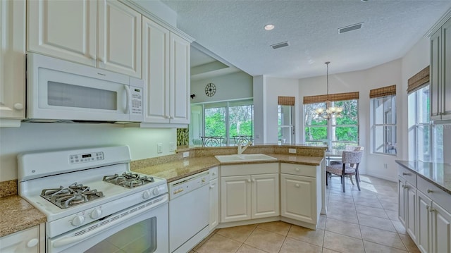 kitchen featuring white appliances, sink, decorative light fixtures, a notable chandelier, and kitchen peninsula