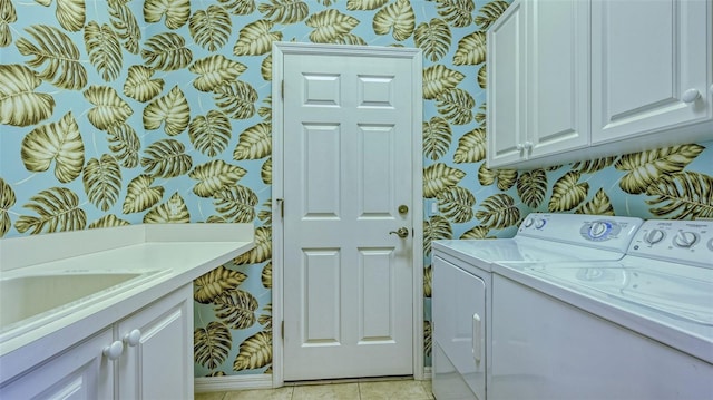 washroom featuring washing machine and dryer, light tile patterned floors, and cabinets