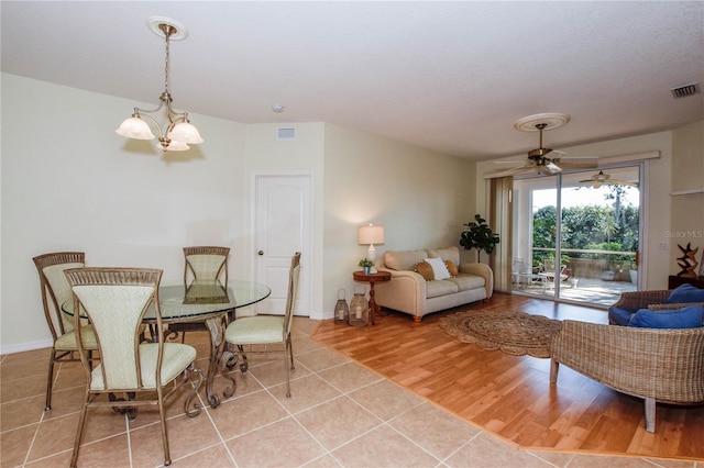 living room featuring ceiling fan with notable chandelier and light wood-type flooring