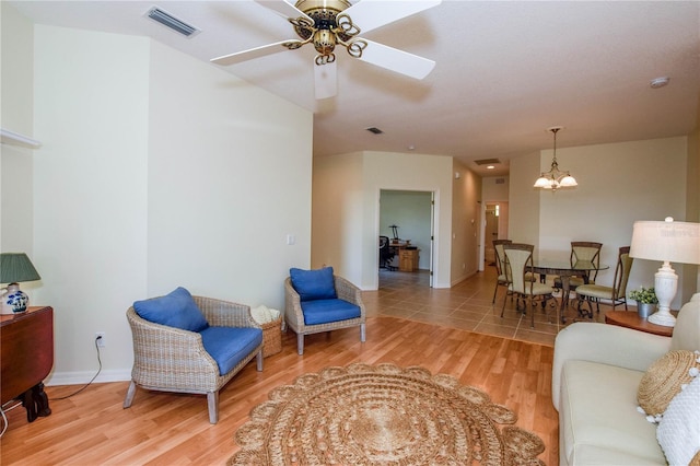 living room featuring ceiling fan with notable chandelier and light wood-type flooring