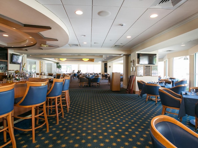 interior space with indoor bar, ornamental molding, and a healthy amount of sunlight