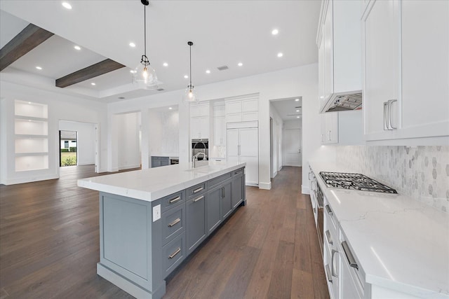 kitchen featuring beam ceiling, hanging light fixtures, white cabinets, and a large island