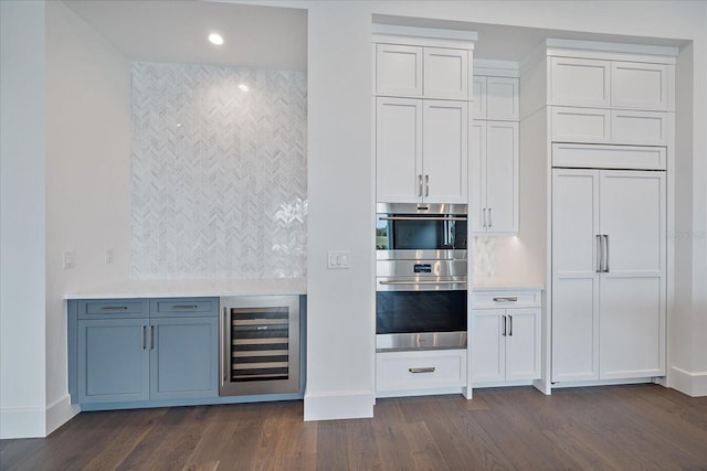 kitchen with white cabinetry, stainless steel double oven, paneled fridge, dark hardwood / wood-style floors, and wine cooler