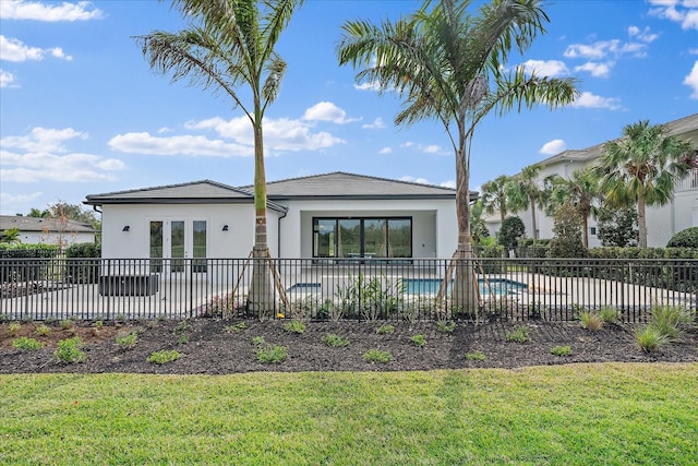 rear view of property with a patio area, a fenced in pool, and a yard